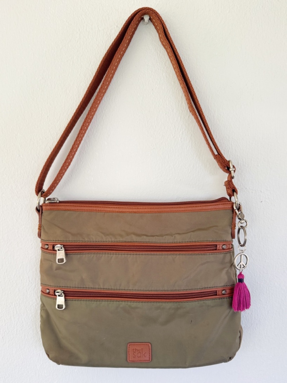 The Sak army green nylon brown leather trim peace sign tassel crossbody bag